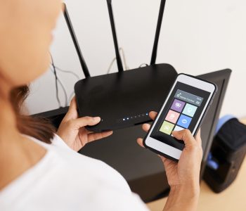 Hands of woman connecting smart home application on her phone to wi-fi router